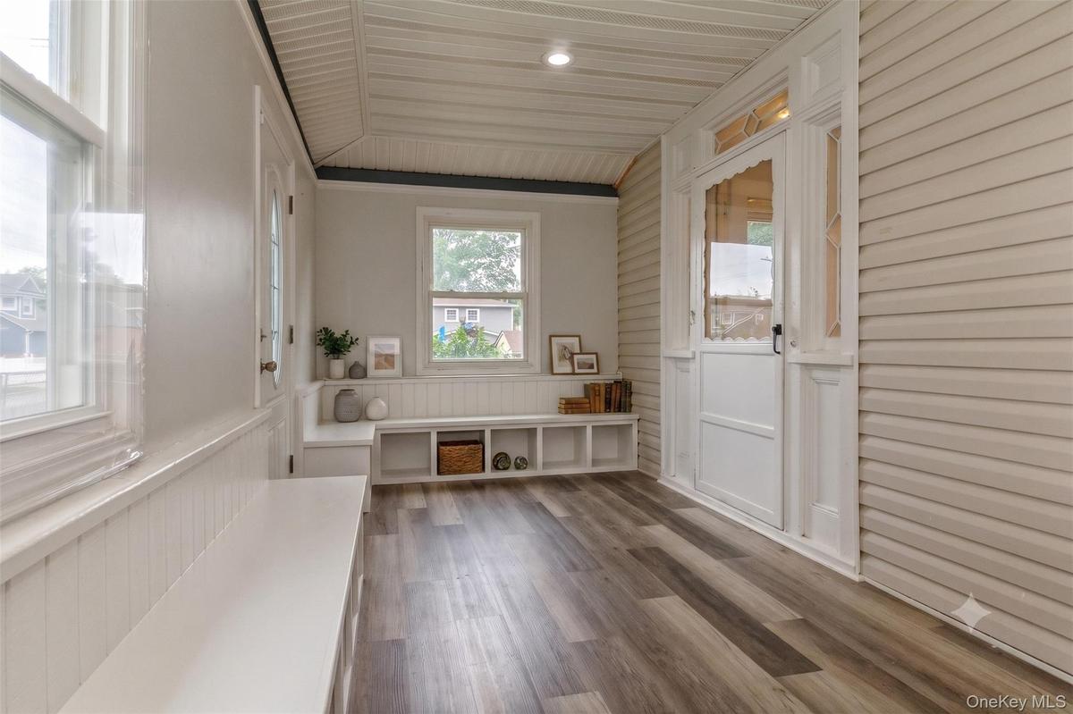 Entryway featuring wood-finish flooring, white paneled walls, and a built-in bench