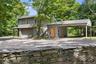 Detached garage with one-bedroom apartment above, covered carport, and EV charging station