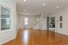 Expansive living area featuring warm wood-finish flooring, recessed lighting, white trim, and a staircase with white balusters