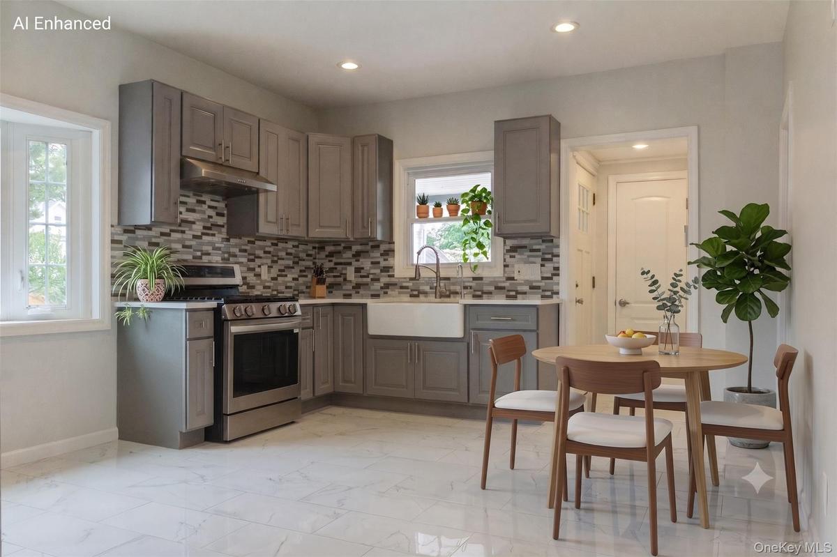 Modern kitchen featuring grey cabinetry, stainless steel appliances, a mosaic tile backsplash, a farmhouse sink, and white tile flooring (virtually st