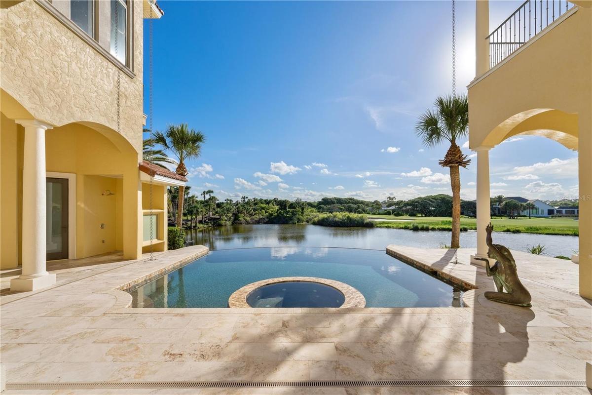 The infinity-edge pool and elevated spa appear to spill seamlessly into the water beyond, creating a resort-inspired retreat designed for both relaxat