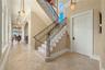 A striking architectural centerpiece, the sweeping staircase draws the eye upward while artisan ironwork and soft natural light create a memorable fir