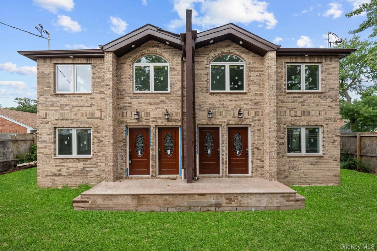 Two-story brick facade featuring multiple entry doors with decorative glass inserts, arched windows on the second level, rectangular windows on both l