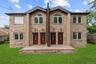 Two-story brick facade featuring multiple entry doors with decorative glass inserts, arched windows on the second level, rectangular windows on both l