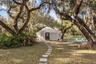 A winding stepping-stone path beneath moss-draped oaks leads to the yurt.