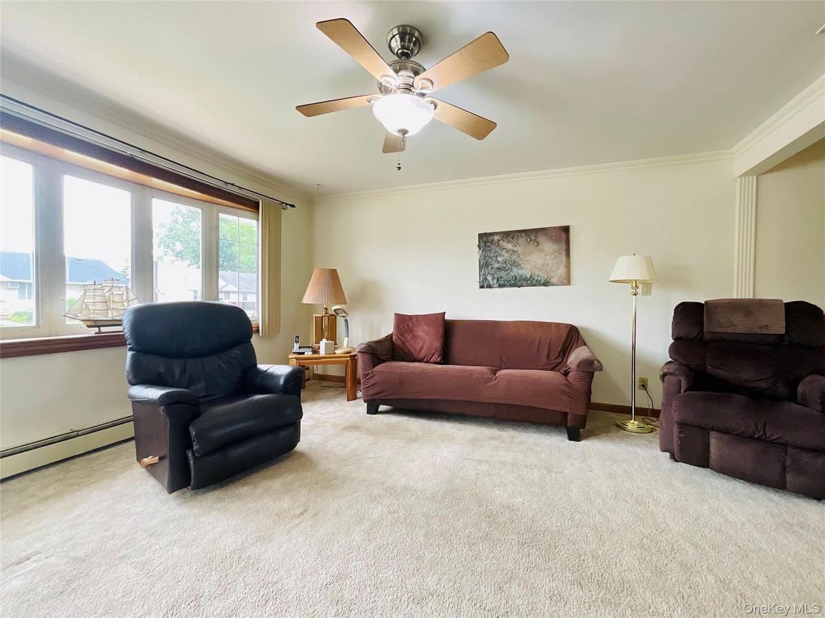 Spacious living area featuring light-toned carpeting and a multi-pane bay window.