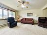 Spacious living area featuring light-toned carpeting and a multi-pane bay window.