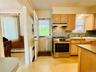Kitchen featuring light wood-finish cabinetry, stainless steel range, with direct access to rear deck.