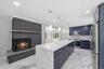 Spacious kitchen with a large waterfall island featuring a quartz countertop and navy cabinetry, complemented by stainless steel appliances, recessed 