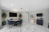 Spacious dining area featuring large format marble-look tile flooring, wainscoting details, a built-in beverage bar with wine storage, and a recessed 