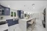 Open-concept kitchen featuring an expansive central island with a waterfall edge, quartz countertops, and blue shaker cabinetry