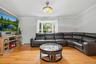 Living area featuring wood-finish flooring, a bay window with natural light, light gray wall paint, and white crown molding