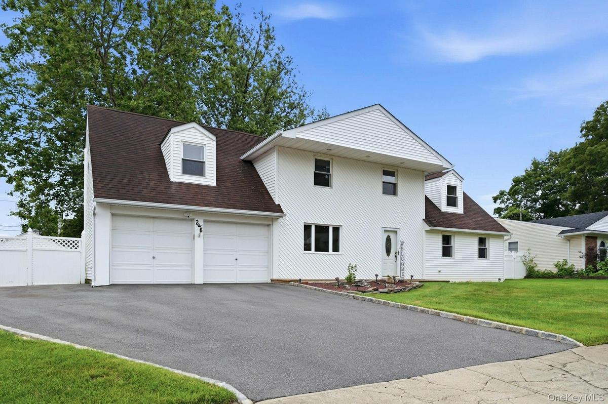 White siding exterior with a dark shingle roof and multiple dormer windows
