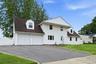 White siding exterior with a dark shingle roof and multiple dormer windows