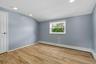 Spacious room with wood-finish flooring, recessed lighting, and a white paneled door