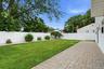 Expansive backyard featuring a paver patio, a lush lawn, and a white privacy fence