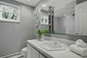 Bathroom featuring a white vanity with integrated sink, a medicine cabinet with mirrored doors, a window with blinds, and recessed lighting