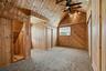 Vaulted wood-paneled room featuring patterned carpet flooring, a window, track lighting, and a ceiling fan