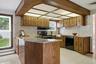 Kitchen featuring wood-finish cabinetry, light-toned tiled backsplash, and granite-style countertops