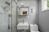 Sleek bathroom featuring a glass-enclosed shower with white marble-look tile, a wall-mounted rectangular sink, and a mirrored medicine cabinet