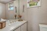 Bathroom vanity featuring an integrated sink with a chrome faucet, a large wall-mounted mirror, and a window with wood-finish blinds