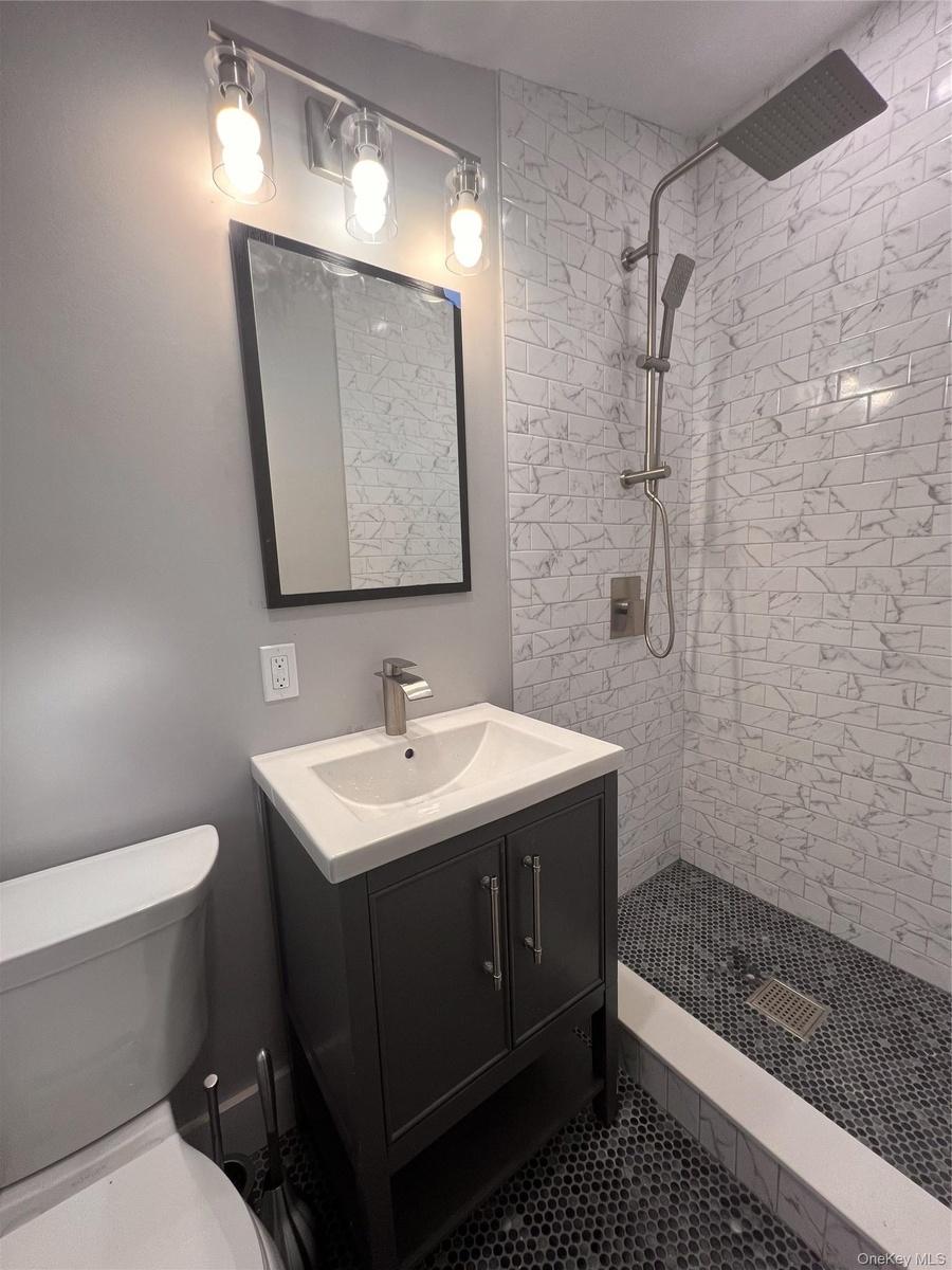 Bathroom with vanity, tiled shower, and tile patterned flooring