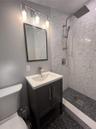 Bathroom with vanity, tiled shower, and tile patterned flooring
