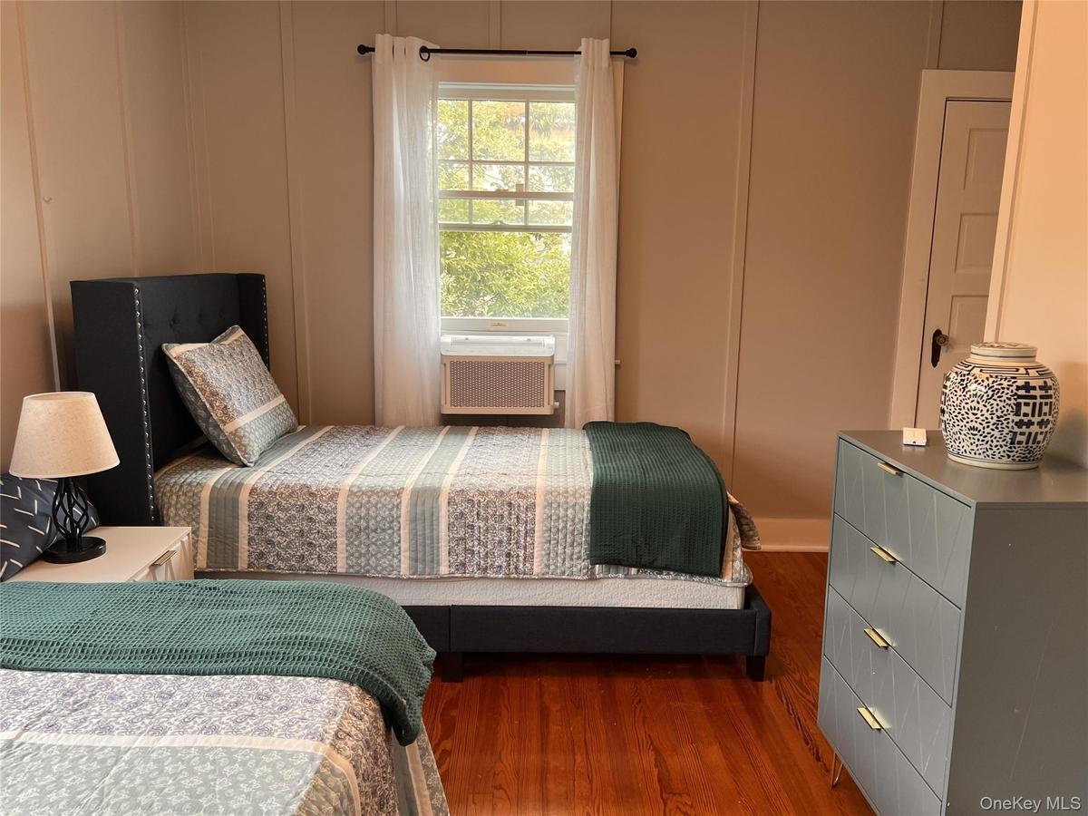 Bedroom featuring dark wood-style flooring and a decorative wall