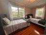 Bedroom featuring ornamental molding, wood finished floors, and a decorative wall