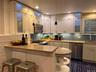 Kitchen with a peninsula, stainless steel appliances, a kitchen bar, decorative backsplash, and light stone countertops