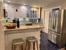 Kitchen with a peninsula, stainless steel appliances, a kitchen bar, decorative backsplash, and light stone countertops