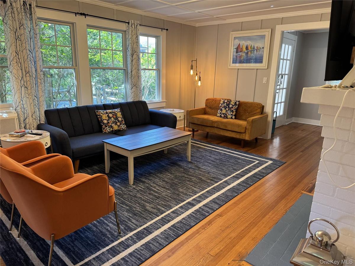 Living room with wood finished floors, healthy amount of natural light, ornamental molding, and a chandelier