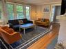 Living room with wood finished floors, healthy amount of natural light, ornamental molding, and a chandelier