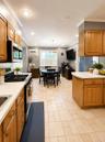 Open-concept kitchen and dining area featuring light wood cabinetry, light-toned tile flooring, and white countertops