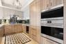 Bleached walnut veneer cabinets w/ bookmarked grain, double ovens & drink station
