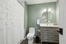 Bathroom featuring a gray vanity with a white countertop, a decorative mirror, and a two-light fixture