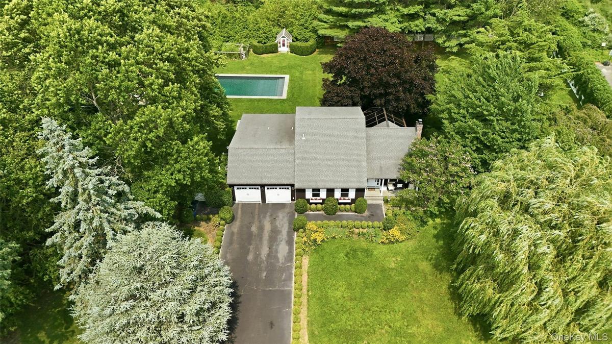 Ranch-style residence featuring a prominent two-car garage, asphalt driveway, and a shingle roof