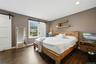 Spacious primary bed-room featuring dark wood-finish flooring, recessed lighting, and a window with white trim, plantation style shutter as window-tre