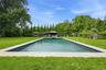 Rectangular swimming pool with a light-colored coping, surrounded by expansive green lawn