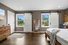 Hardwood-style flooring throughout this space features two windows with barn door style coverings, recessed ceiling lighting, and a solid white interi
