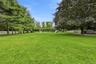 Expansive green lawn framed by mature trees and a white picket fence