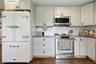 Kitchen featuring stainless steel appliances, white shaker-style cabinetry, dark countertops, a white subway tile backsplash, and wood-finish flooring