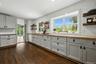 Spacious kitchen featuring gray shaker-style cabinetry with dark hardware, wood-finish countertops, and white subway tile backsplash