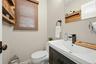 1/2 Bathroom featuring a dark wood-finish vanity with an integrated sink, matte black faucet, and coordinating towel ring