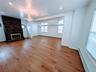 Unfurnished living room featuring a baseboard radiator, an inviting chandelier, baseboards, and light wood-type flooring