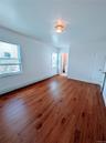 Empty room with a baseboard heating unit, baseboards, and wood finished floors