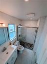 Bathroom with toilet, a stall shower, vanity, and tile walls