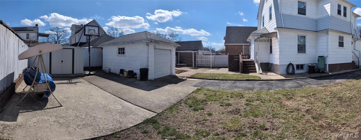 View of home's exterior featuring fence, an outdoor structure, a garage, and a storage unit
