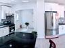 Kitchen with tasteful backsplash, under cabinet range hood, white cabinetry, and stainless steel appliances