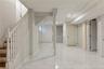 Finished basement space featuring white marble-look tile flooring, recessed ceiling lighting, a white painted staircase with wood treads, and multiple